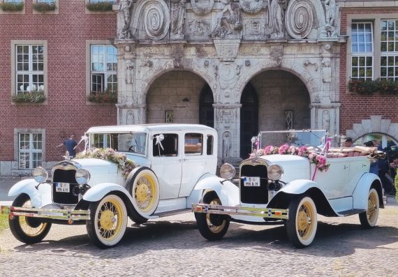 brautlimousine und brautcabrio mit blumengirlanden geschmueckt