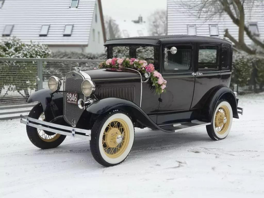 brautlimousine hochzeitsauto ford a town sedan baujahr 1930 farbe maroon kastanienbraun mit blumengirlande im schnee
